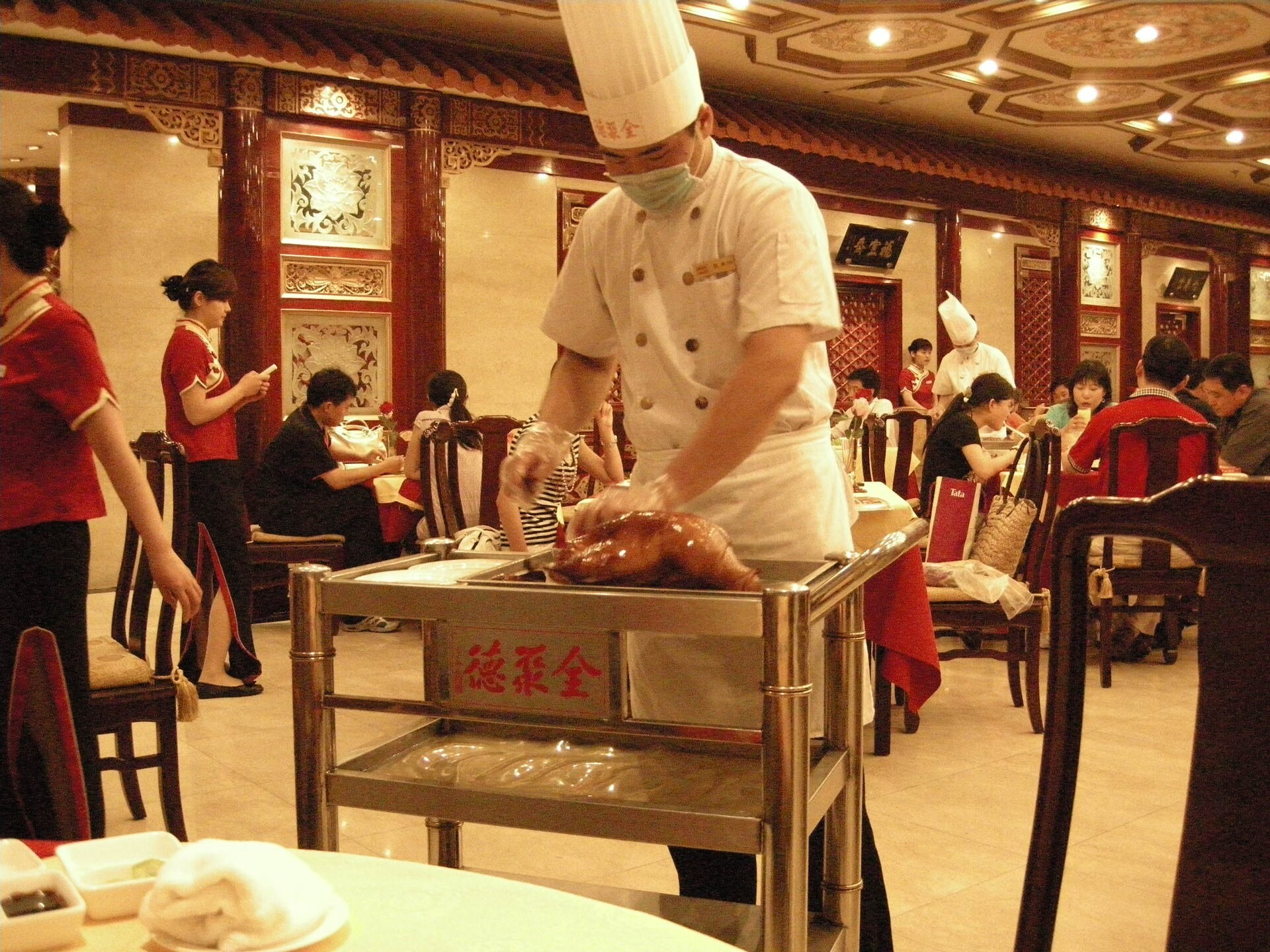 A chef carving roast duck tableside in Beijing