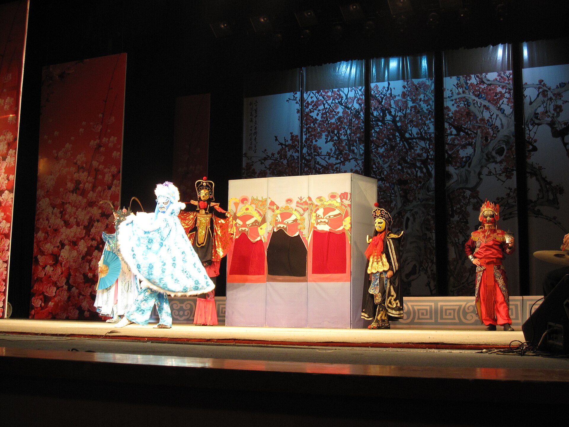 Performers in painted masks during a Sichuan opera face-changing sequence on a Chengdu stage