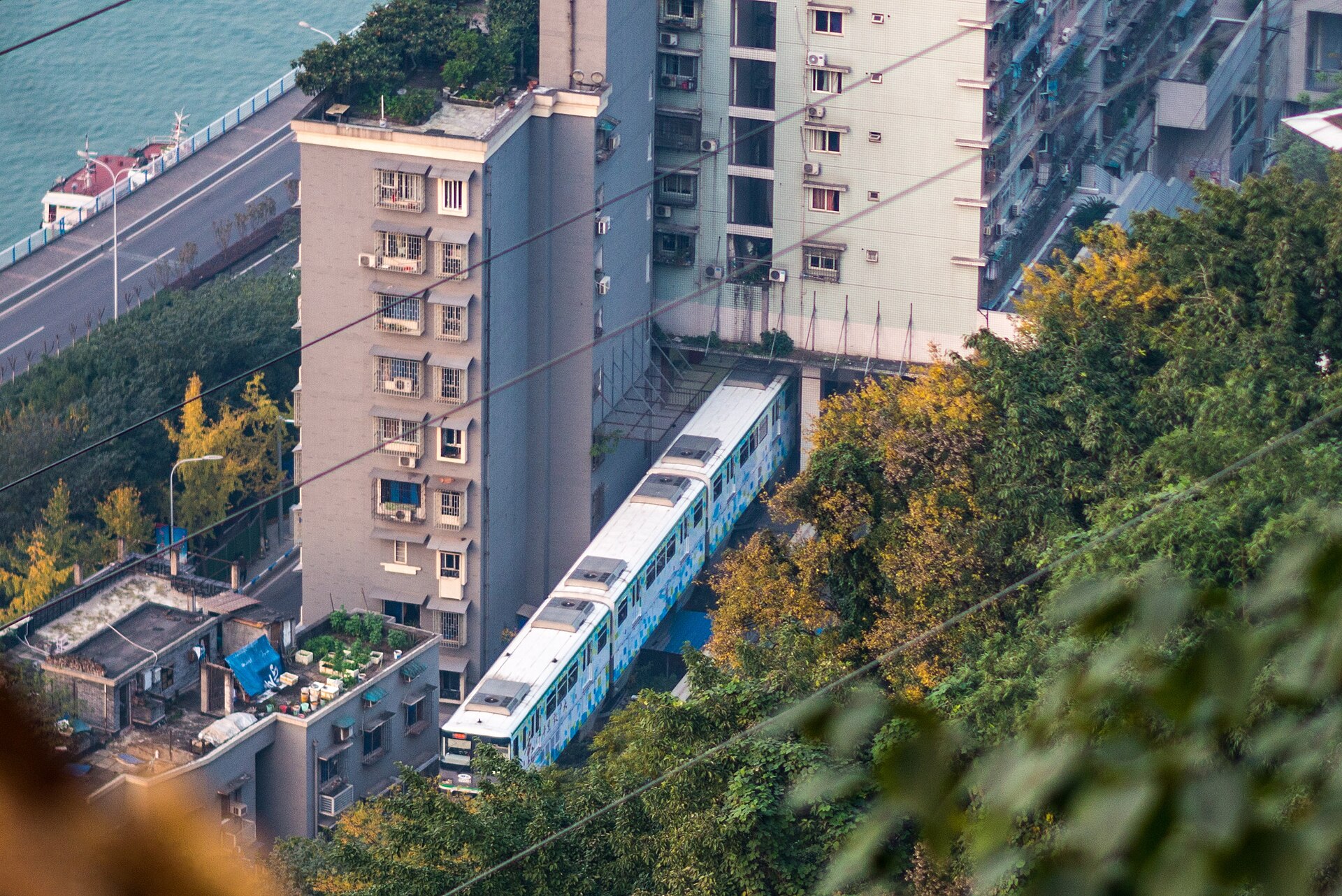 A Line 2 monorail train passing through the residential building at Liziba station in Chongqing, the Jialing River below