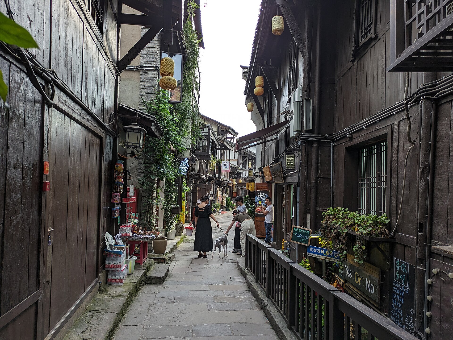 A stone-flagged shopping lane in Ciqikou old town, Chongqing, lined with timber-fronted snack shops