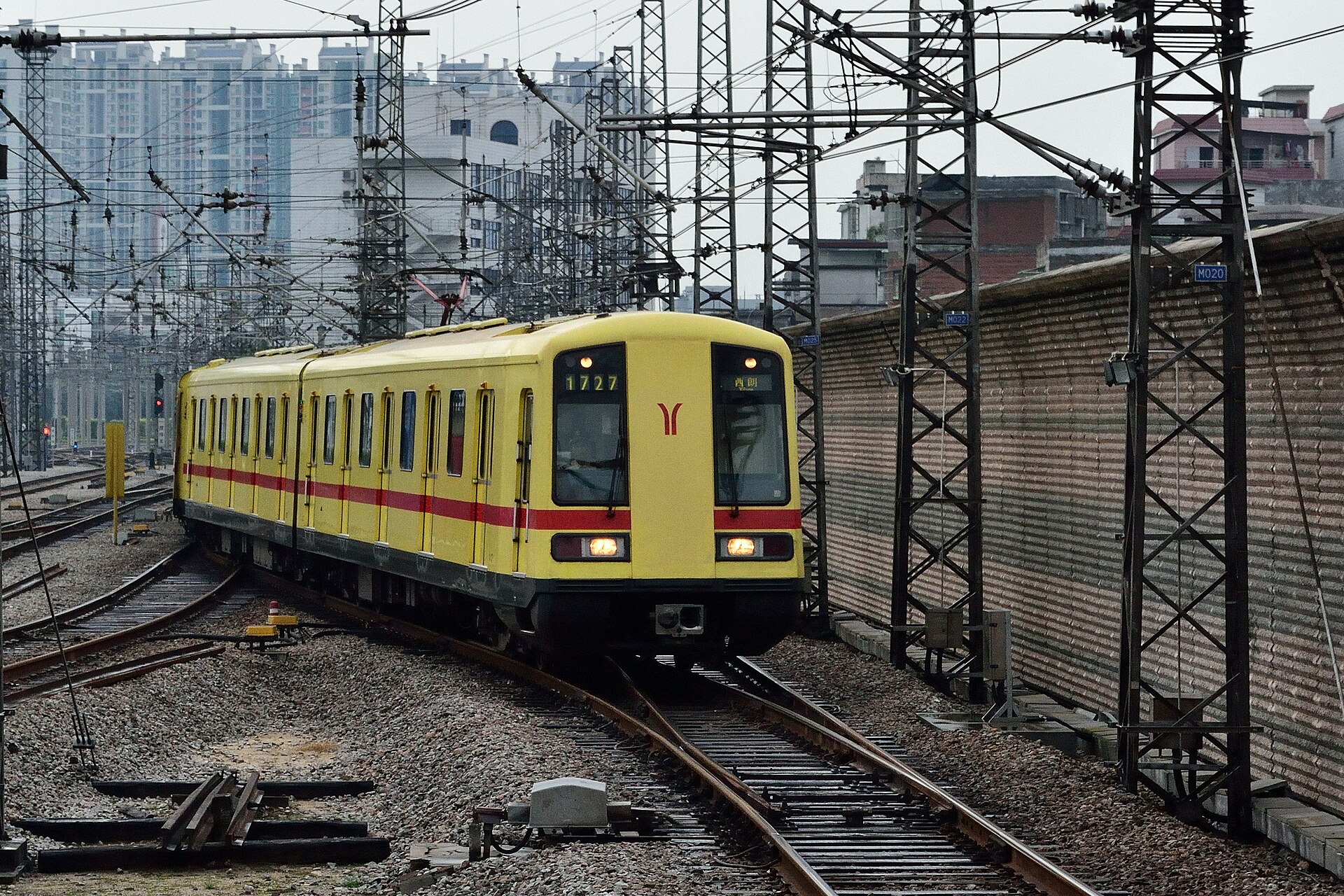A yellow Guangzhou Metro Line 1 train with the ram-horn logo approaching Xilang station