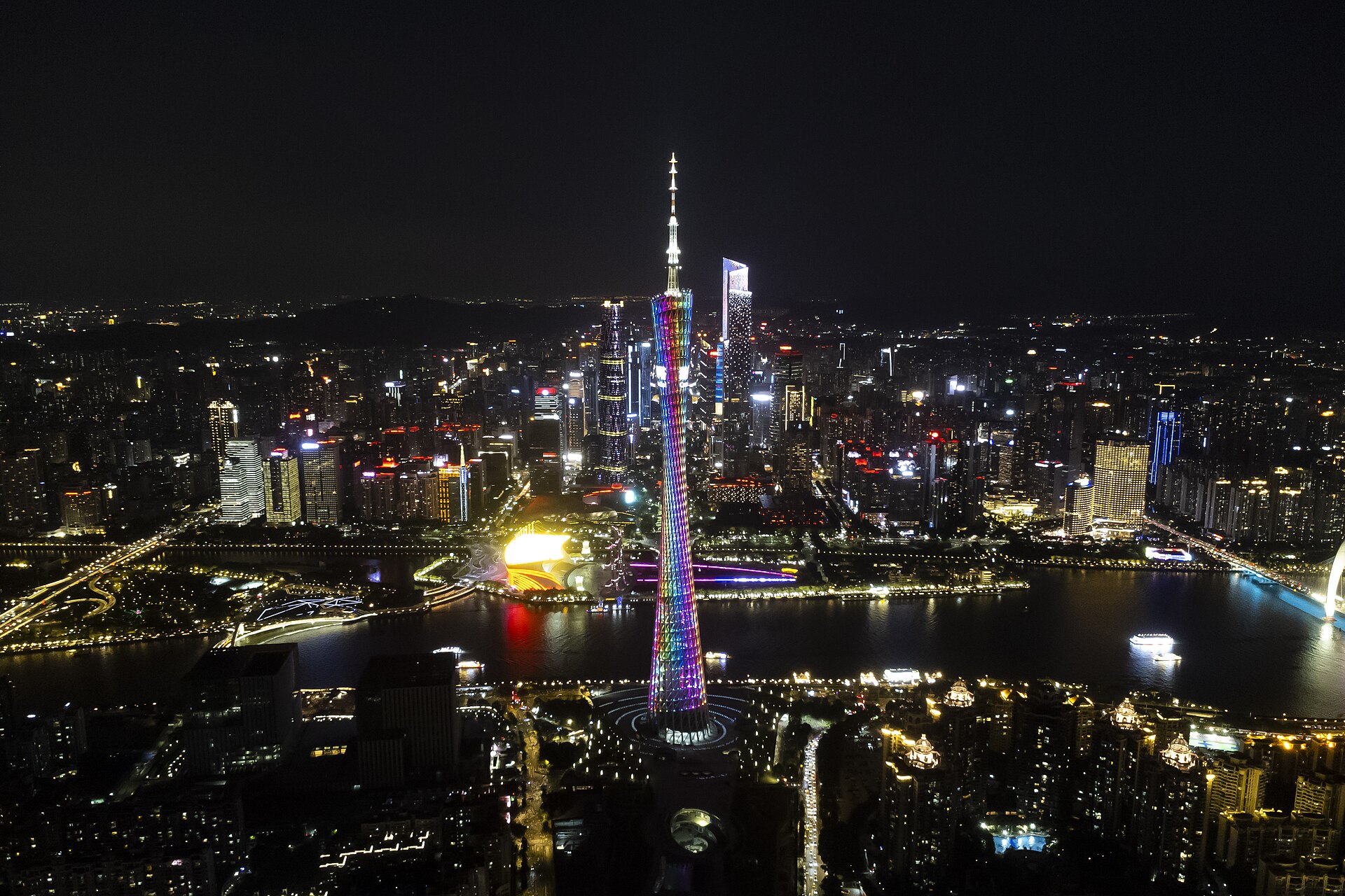 Canton Tower lit in rainbow colours above the Pearl River at night, with Zhujiang New Town behind it