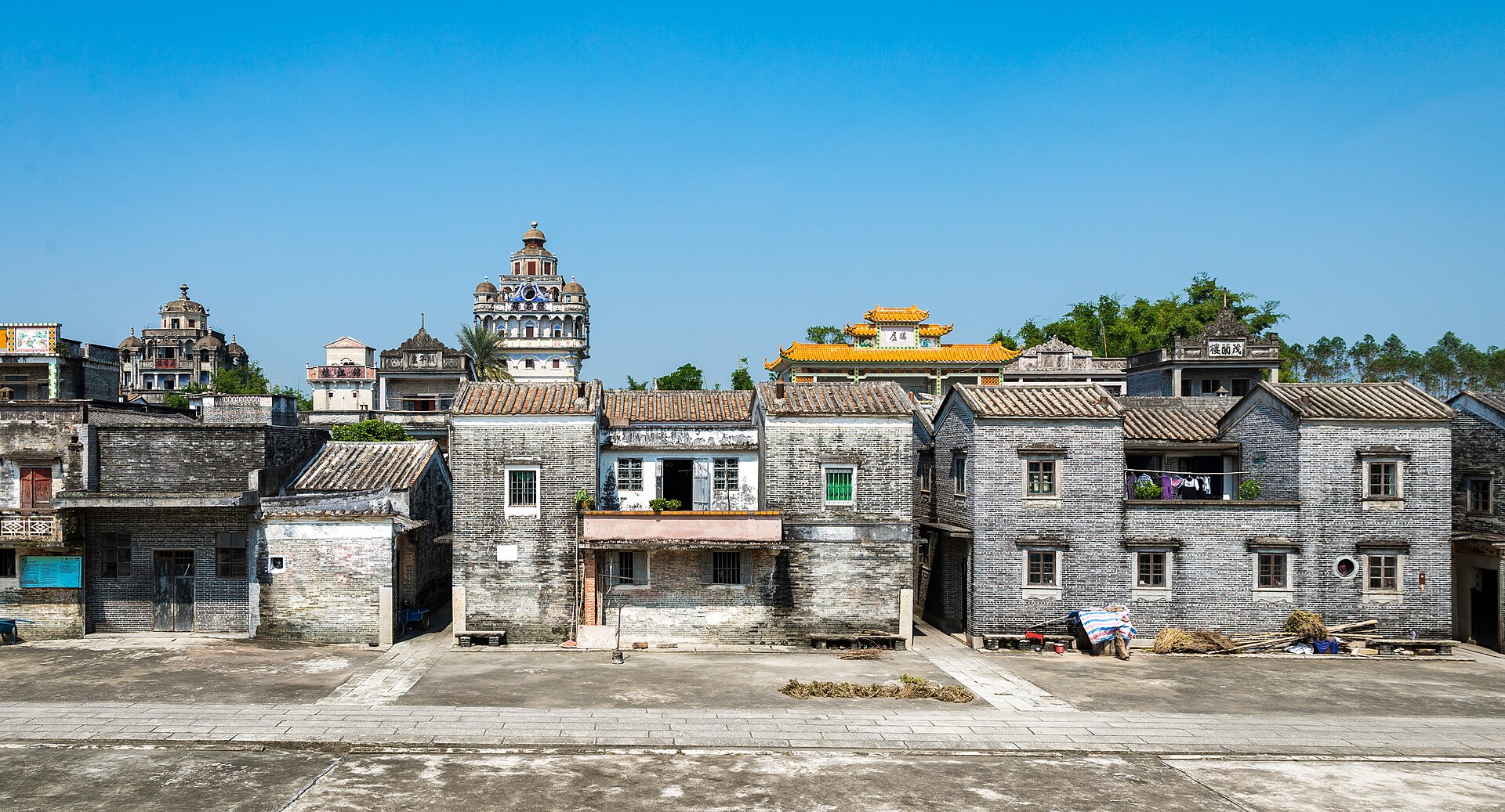 Jinjiangli village in Kaiping, grey-brick houses in front and the ornate Ruishi Lou diaolou rising behind them