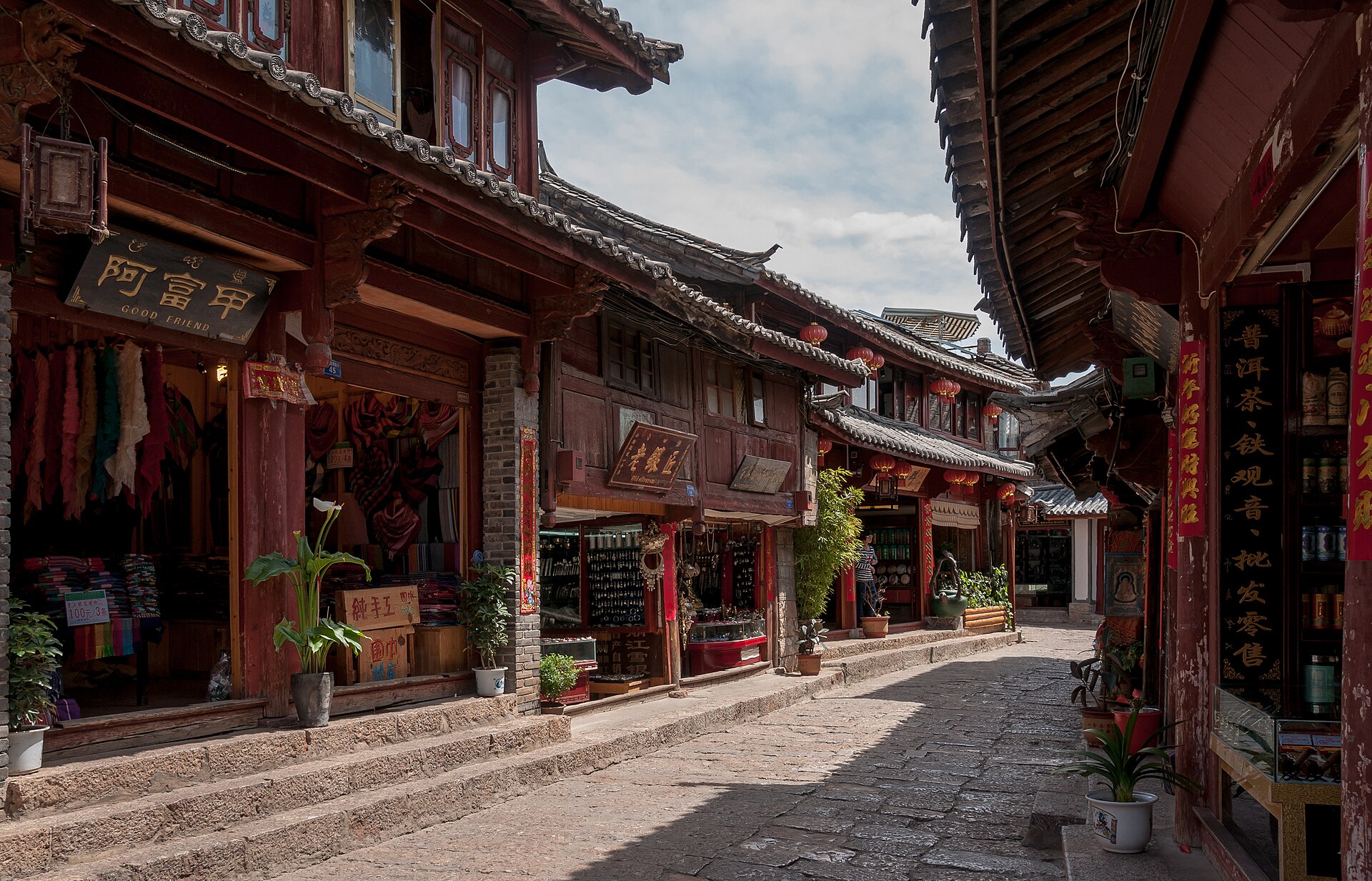 A cobbled shopping lane in Lijiang old town lined with textile, silver and tea shops