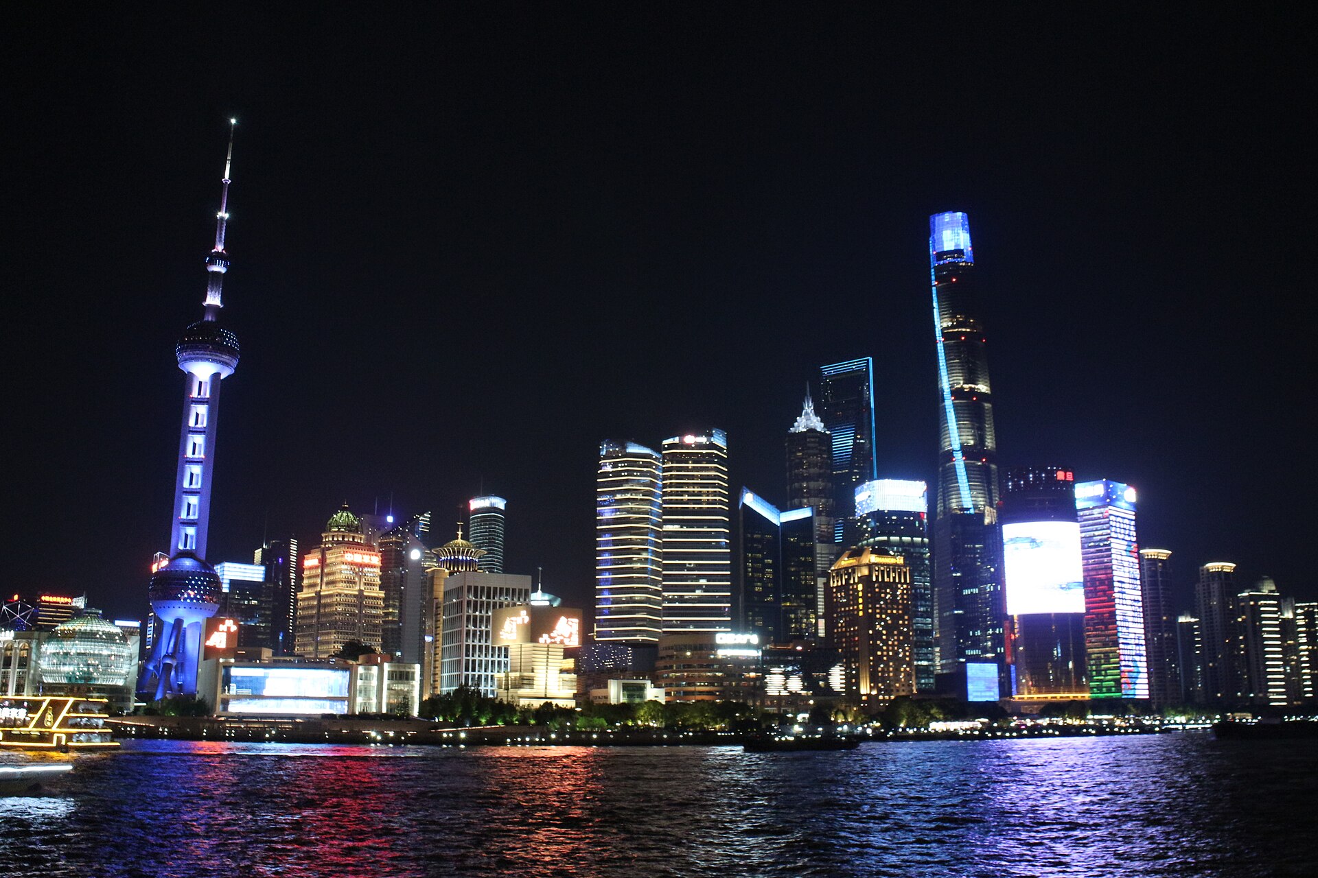 Lujiazui lit up at night across the Huangpu, seen from the Bund — the view the rooftop bars sell