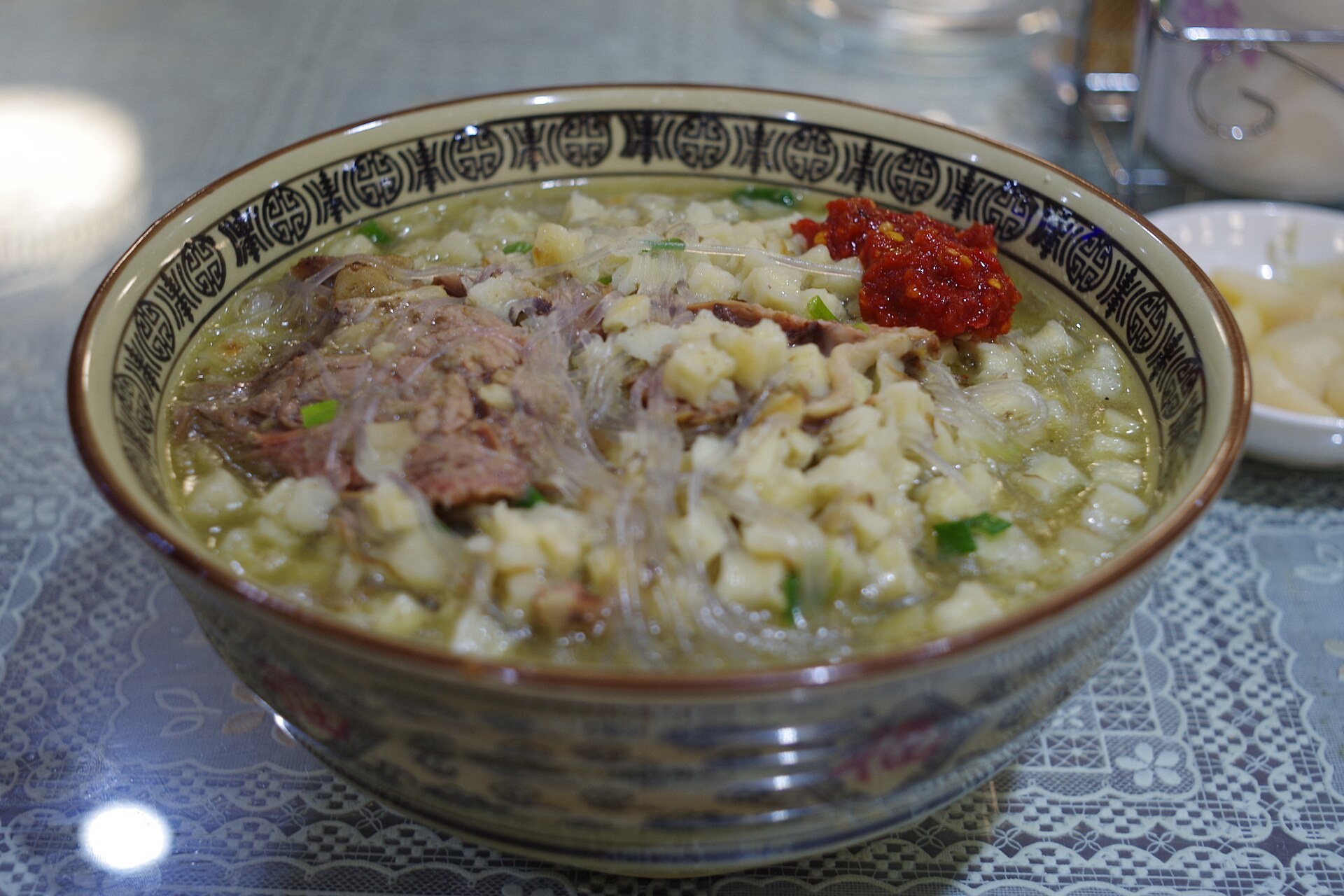 A cook tearing flatbread into a bowl for yangrou paomo in Xi'an's Muslim Quarter