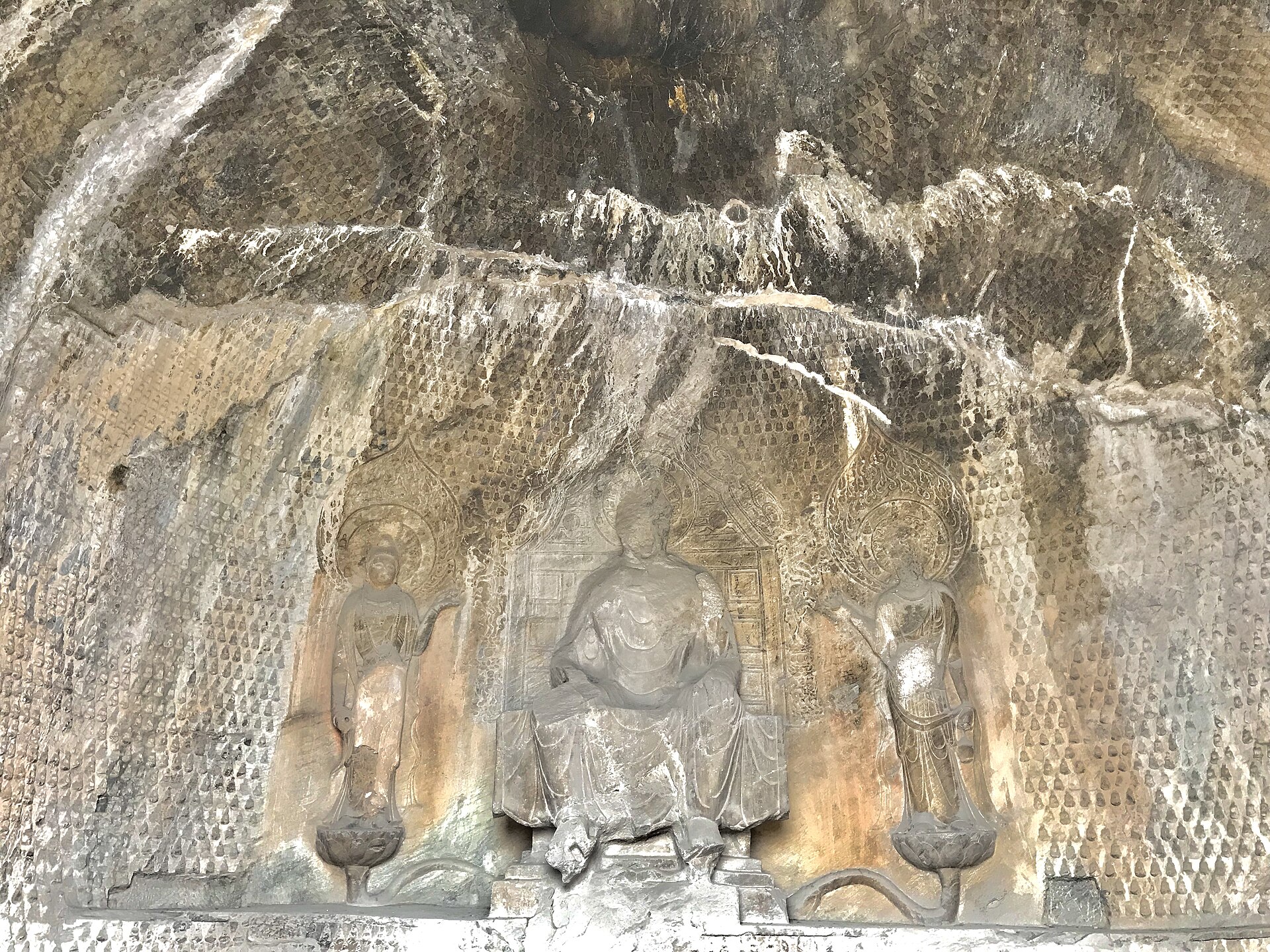 A carved Buddha triad inside a grotto at the Longmen Grottoes, Luoyang