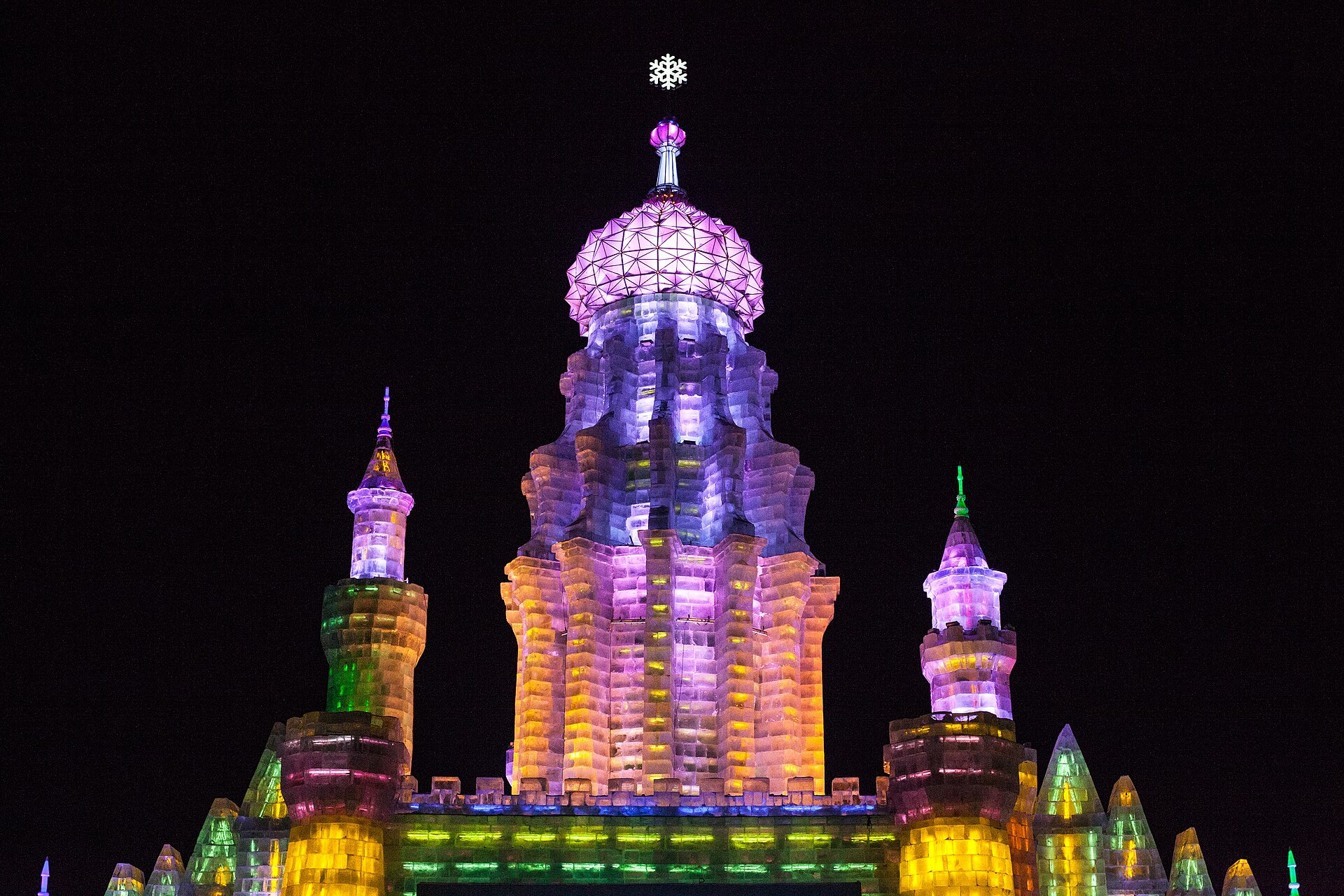 A color-lit ice tower glowing at night at Harbin's Ice and Snow World
